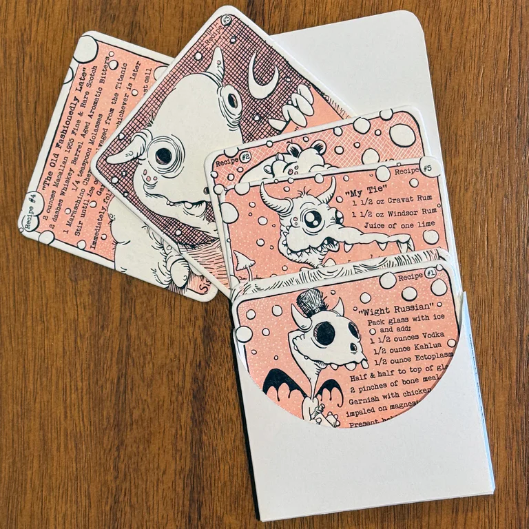 The handmade folio opened to reveal a layered set of pink and black letterpress monster coasters.