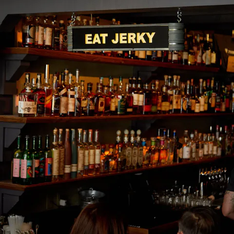 The back bar at Third Rail in San Francisco beneath an Eat Jerky sign.