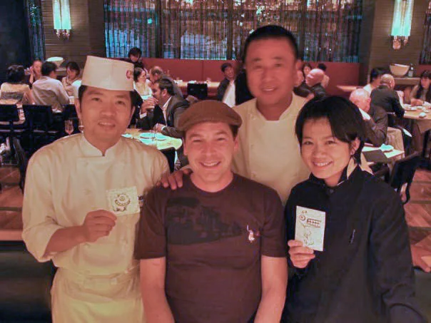 Dylan Sisson smiling with Nobu Matsuhisa and two members of the restaurant staff, who hold small hand-drawn monster coasters.