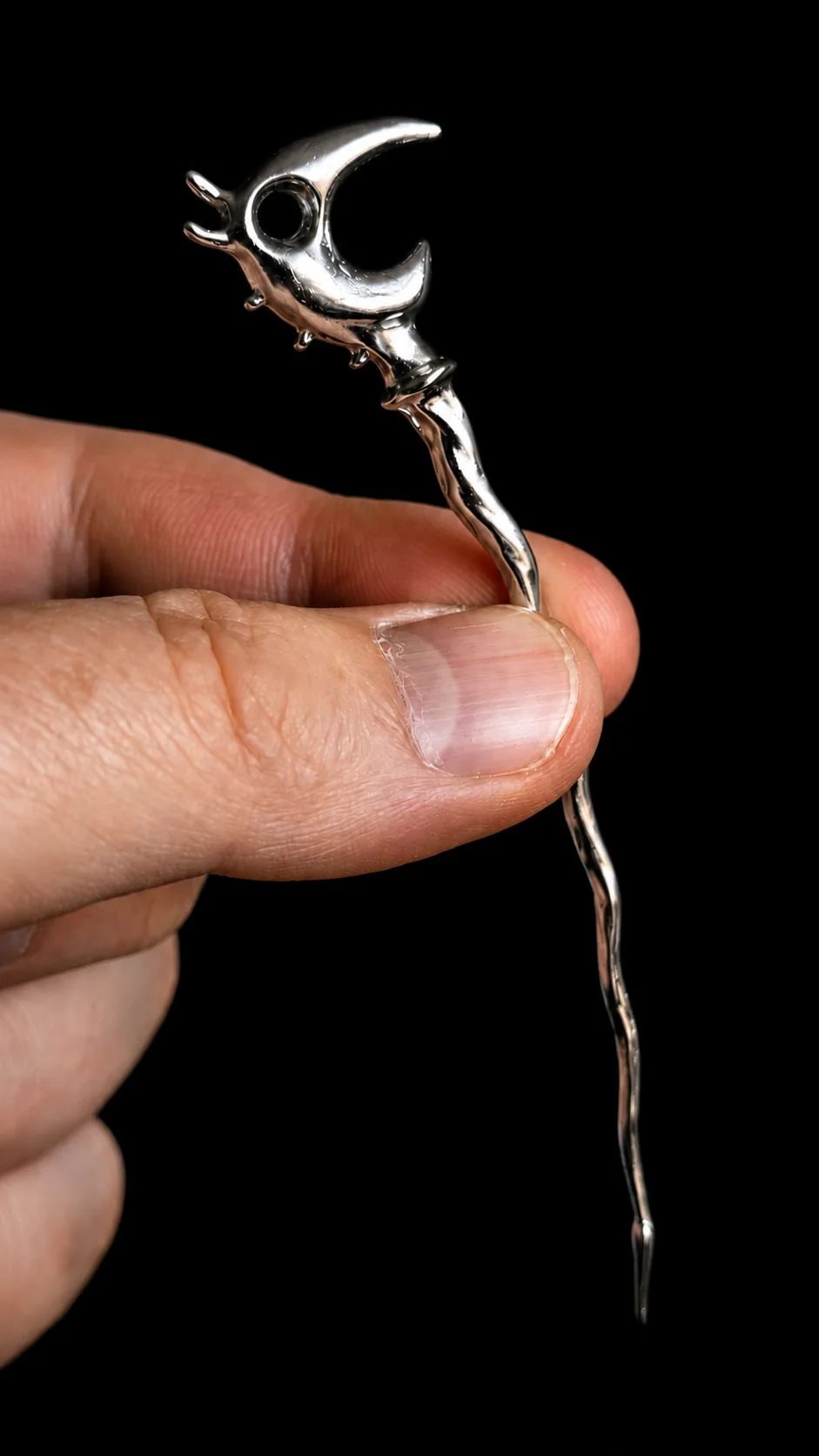 A full chrome Dragon Pick held between a thumb and forefinger to show its scale.