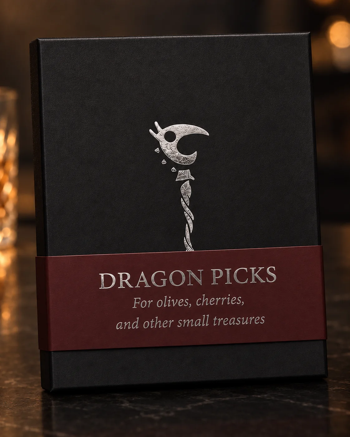 The finished black Dragon Picks box with its burgundy wrap, photographed against a warm bar background.