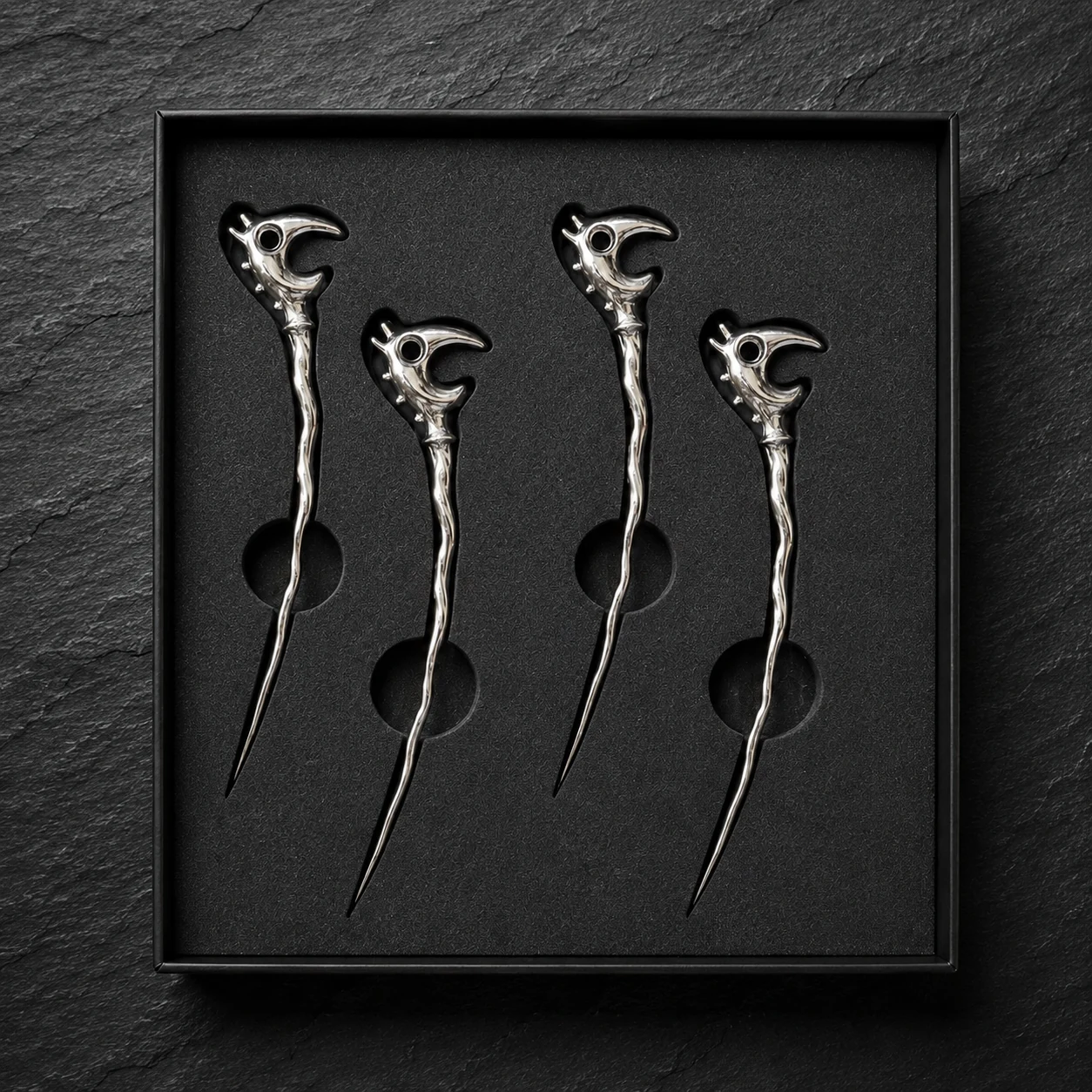 Four chrome Dragon Picks arranged in a fitted black foam insert inside an open presentation box.