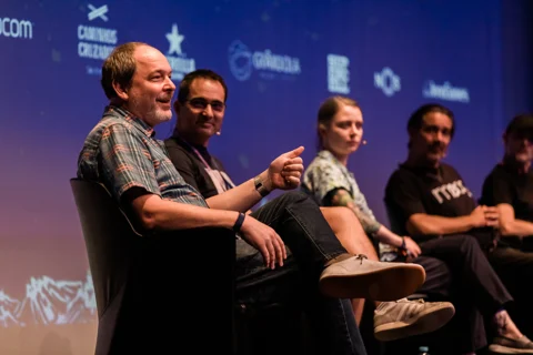 Dylan Sisson smiling and gesturing during a panel discussion with fellow speakers.