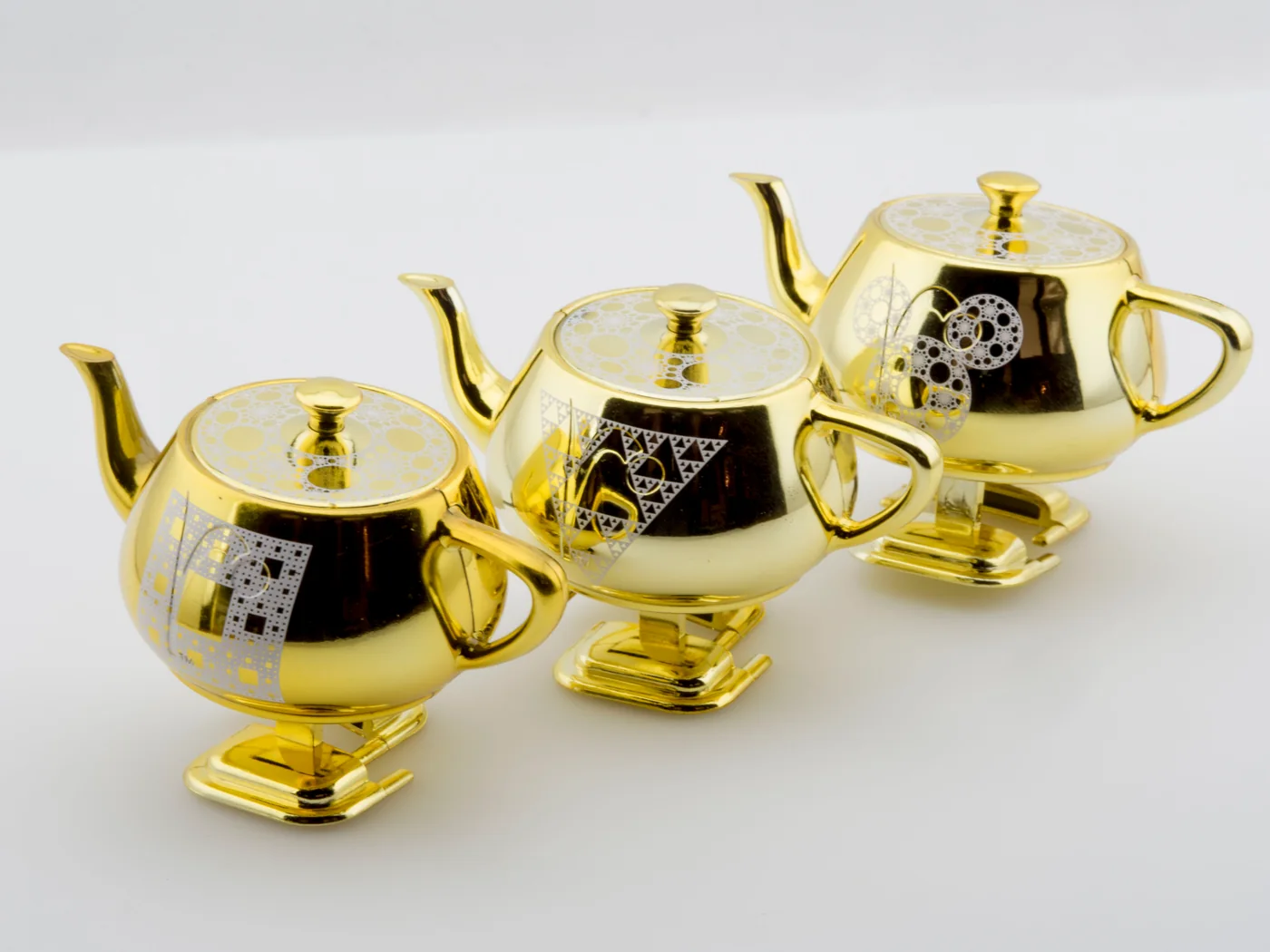 Sierpinski series Walking Teapot editions photographed on a pale studio background.